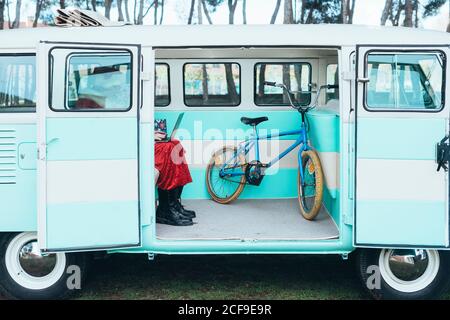 Side view of man in costume of Santa Claus typing on laptop while sitting in van with bicycle Stock Photo