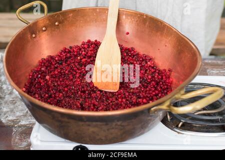 Cooking Finnish lingonberry jam with spices in a copper basin on a gas stove Stock Photo