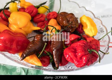 Various types of hot yellow, red, brown peppers in a bowl for table decoration Stock Photo