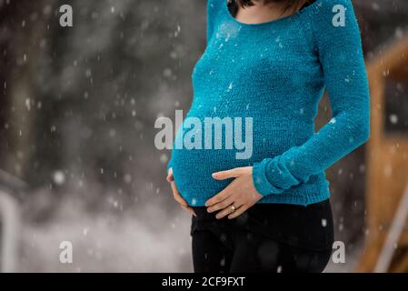 pregnant woman in warm winter clothes standing outside on a snowy winter  day, with hands on her stomach on the background of nature. Concept of  pregna Stock Photo - Alamy