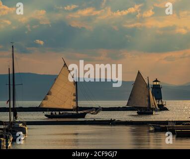 two sloops sailing by the lighthouse on the waterfront of Lake Champlain in Burlington, Vermont Stock Photo