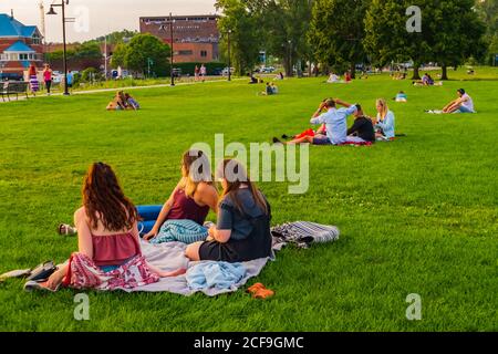 Burlington, Vermont/ USA-August 23, 2020: people sitting on lawn on the shore of Lake Champlain social distancing while they watch the sunset Stock Photo