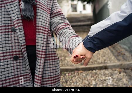 Casual faceless couple holding hands and strolling in city Stock Photo
