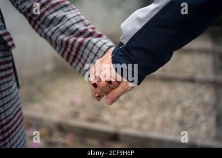 Casual faceless couple holding hands and strolling in city Stock Photo