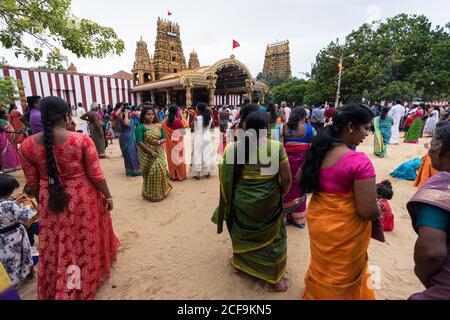 Jaffna, Sri Lanka - August, 9 2019: Young Tamil female in colorful traditional clothes while standing against crowd and temple during Nallur Kandaswamy Kovil Festival Stock Photo