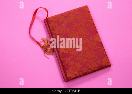 View on isolated notebook with red floral pattern cover and bookmark on pink background with copy space for text Stock Photo