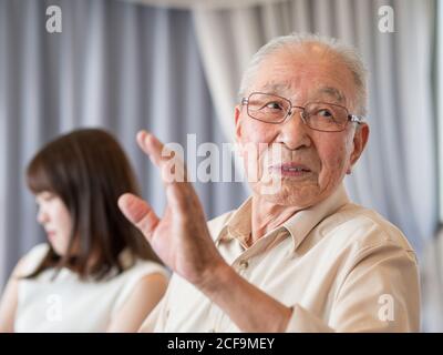 An old man talking animatedly at a family event Stock Photo