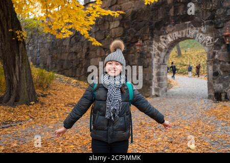Cheerful young Asian Woman throwing yellow maple leaves while standing in patio of Oslo Cathedral in Norway Stock Photo