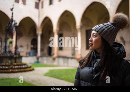 Curious resting Asian woman in warm clothing and hat exploring beautiful ancient Basilica di Sant Antonio di Padova
