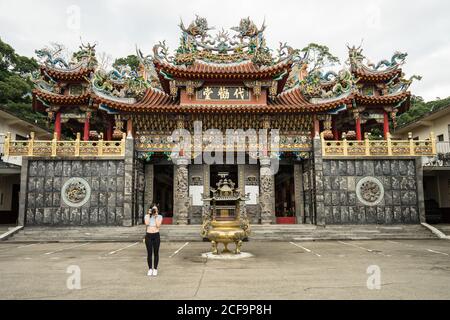 Female traveler in casual wear taking picture in front of camera with beautiful Taoist Temple Dai Quan Tang at Taiwan Stock Photo