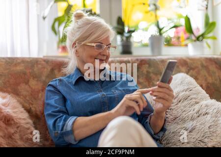 Senior woman using mobile phone at home Stock Photo