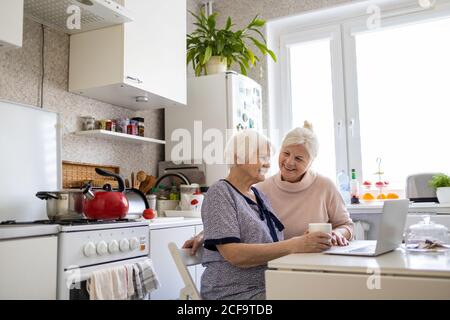 Adult daughter teaching her elderly mother to use laptop Stock Photo