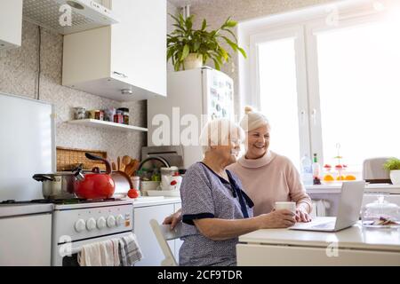 Adult daughter teaching her elderly mother to use laptop Stock Photo