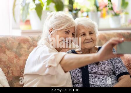 Senior woman and her adult daughter using smartphone together Stock Photo