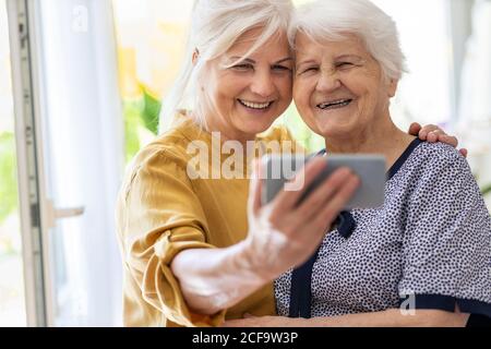 Senior woman and her adult daughter using smartphone together Stock Photo
