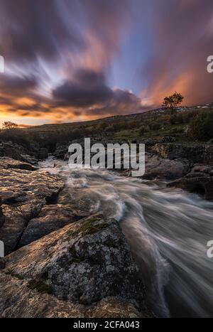 Picturesque view of mountain river streaming through rocky cliffs in calm evening during sunset in autumn Stock Photo