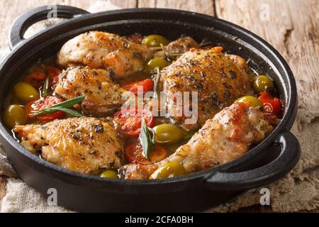 Rustic style chicken baked with green olives, tomatoes and onions, herbs close-up in a pan on the table. horizontal Stock Photo