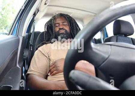 Tired driver resting on long journey. Man sleeps in car for a break. Stock Photo