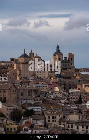 Amazing cityscape with aged stone buildings located on hill on background of cloudy sky in evening Stock Photo