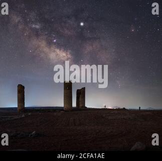 Ancient stone towers on empty sandy ground under dark starry sky with milky way Stock Photo