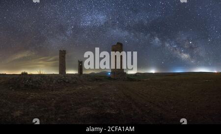 Ancient stone towers on empty sandy ground under dark starry sky with milky way Stock Photo