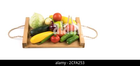 Fresh fruit:tomatoes, cucumbers, zucchini, peppers and cabbage on a white background on a wooden tray. Stock Photo