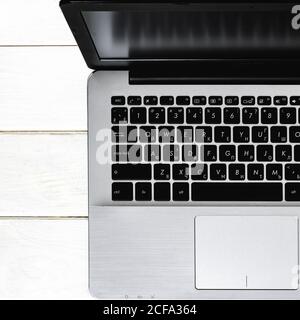 Grey laptop with black keyboard stands on white wood table Stock Photo