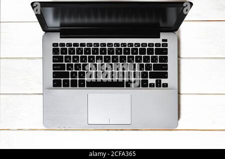 Grey laptop with black keyboard stands on white wood table Stock Photo