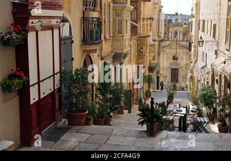 The historic Church of St. Lucy sits at the foot of a pedestrian section of St. Lucia Street lined with shops and restaurants in Valletta, Malta. Stock Photo