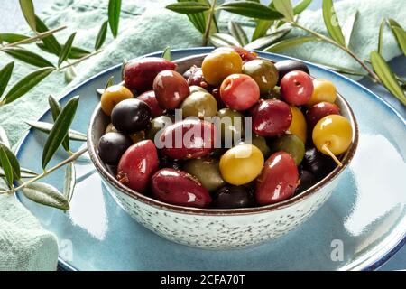 Olives. A variety of green, black and red olives, with leaves, a close-up Stock Photo