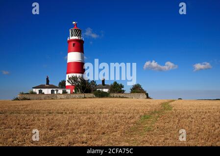 A view of a footpath over farmland by the independently operated lighthouse on the North Norfolk coast at Happisburgh, Norfolk, England, UK. Stock Photo