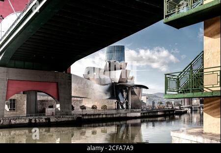 View of channel and bridge with Guggenheim Bilbao Museum on other side of river in daylight Stock Photo