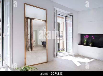 Simple interior of modern living room with white walls, mirror and balcony Stock Photo