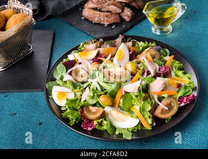 From above of appetizing Spanish tuna salad with boiled eggs and vegetables served on plate on table with various snacks Stock Photo