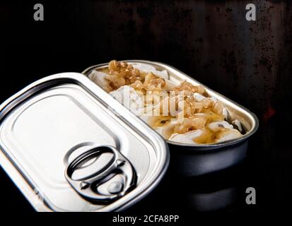 Yummy dish of walnuts with cheese and syrup in tin can on glossy surface against rusty dark background Stock Photo