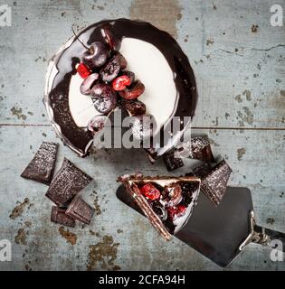Top view black forest cake with chocolate biscuits and cream with cherries placed against shabby background Stock Photo