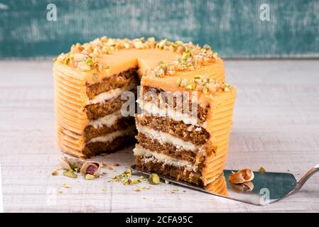 Cake server with piece of delicious carrot cake with pistachios on wooden table Stock Photo