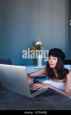 Attractive young stylish Woman in cap using laptop at home Stock Photo