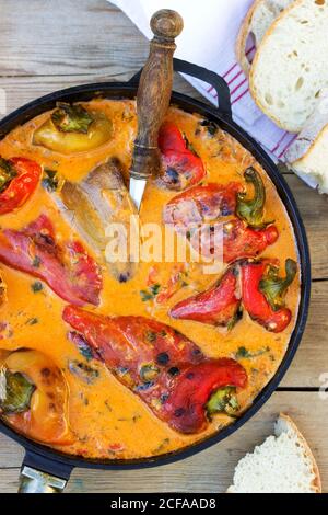 Sweet peppers in tomato and sour cream sauce, a traditional dish in some European countries. Rustic style. Stock Photo