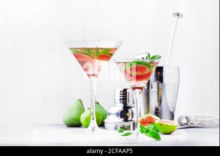 Pink fig martini cocktail in shot glass on gray table with bar tools, selective focus Stock Photo