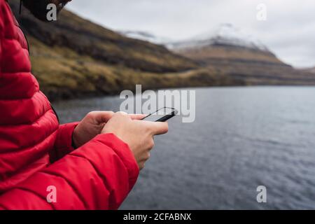 anonymous man using smartphone near a lake in Faroe Island Stock Photo