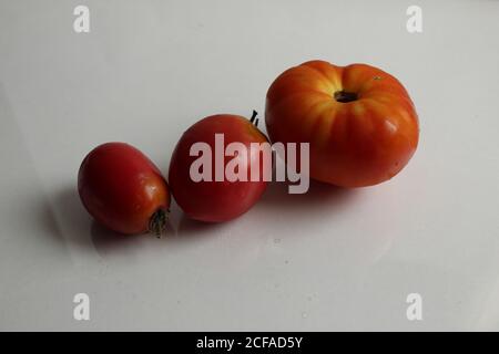 one or more of the three red-orange tomatoes on a white background with copy space Stock Photo