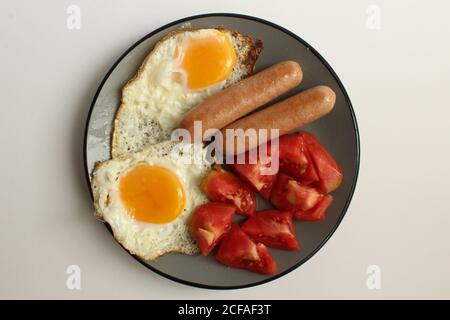 Breakfast eggs sausages salad vegetables red tomatoes on a gray plate on a white light background copy space Stock Photo