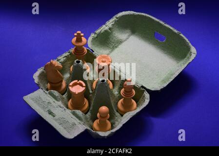 High angle shot of chess plastic pieces in an egg box