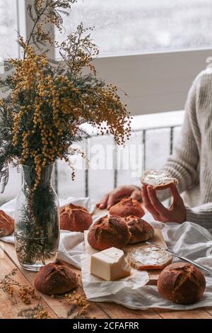 faceless lady spreading butter on bread in kitchen Stock Photo