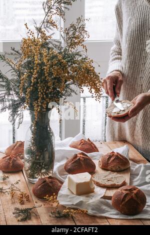 faceless lady spreading butter on bread in kitchen Stock Photo