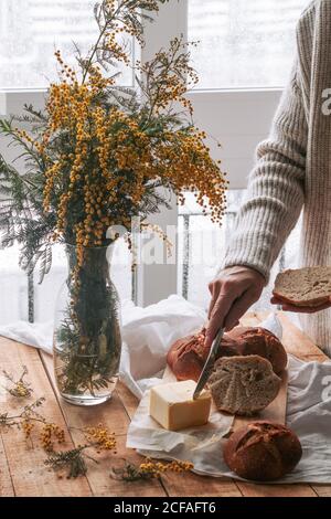faceless lady spreading butter on bread in kitchen Stock Photo
