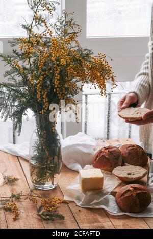 faceless lady spreading butter on bread in kitchen Stock Photo