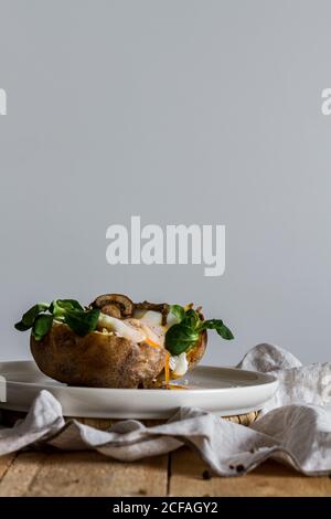 Fried egg on potato on wooden table with fried mushrooms grated cheese and herbs Stock Photo