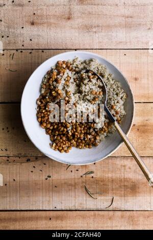 From above white rice mixed with beans in bowl with spoon on wooden rustic table Stock Photo